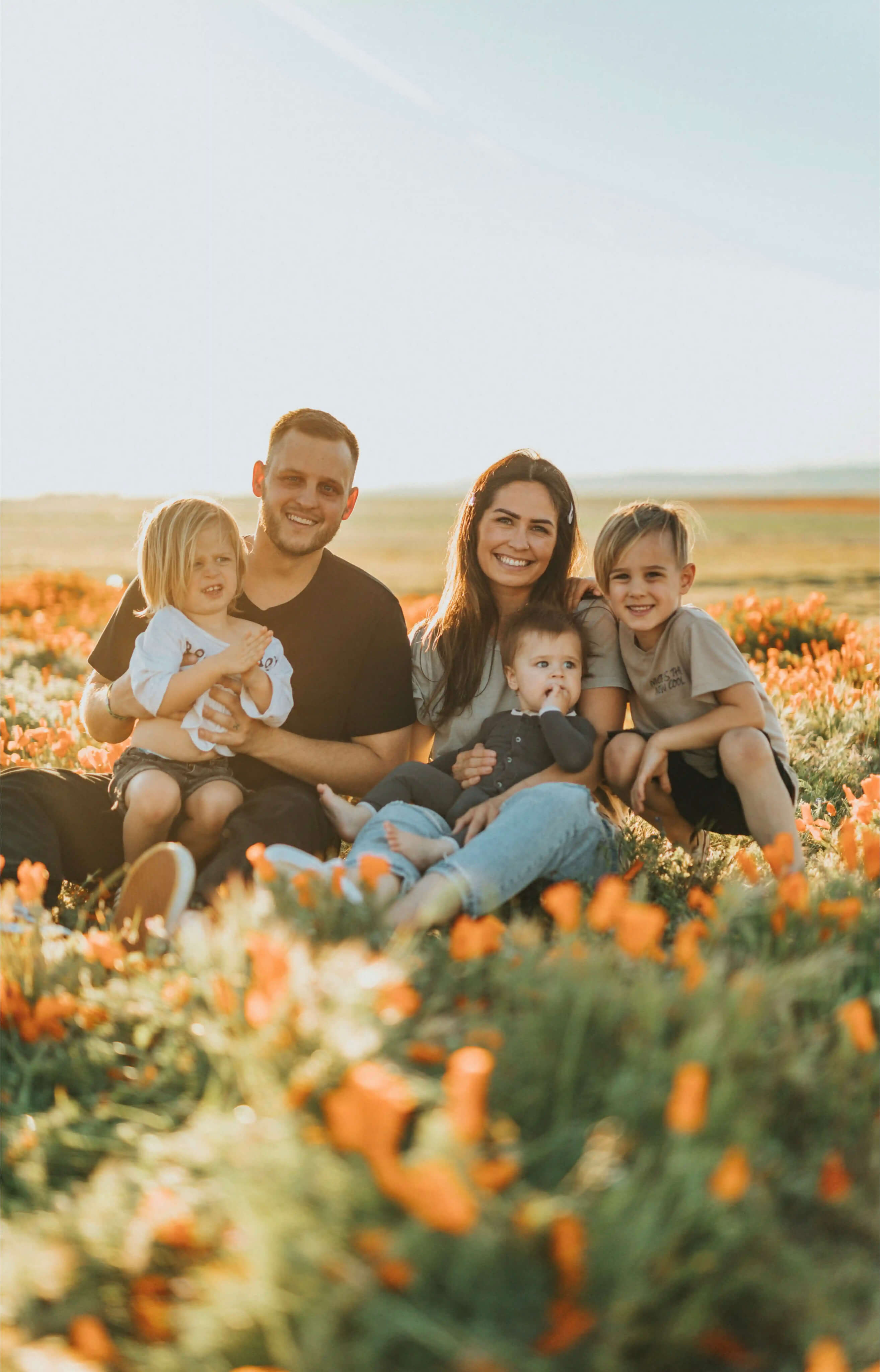 A family sitting in a field of orange flowers