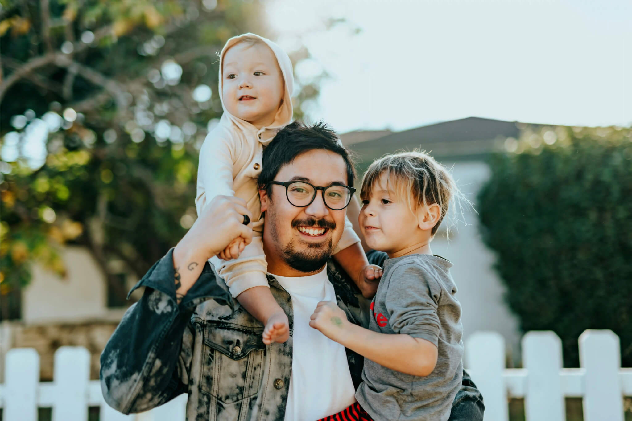 A father holding two young children outside